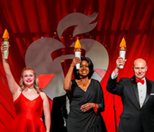 Three people on stage holding up lit torches.